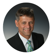 Headshot of Kentucky Farmers Bank VP/ Manager. He is smiling, wearing a suit with a green tie against a grey background.